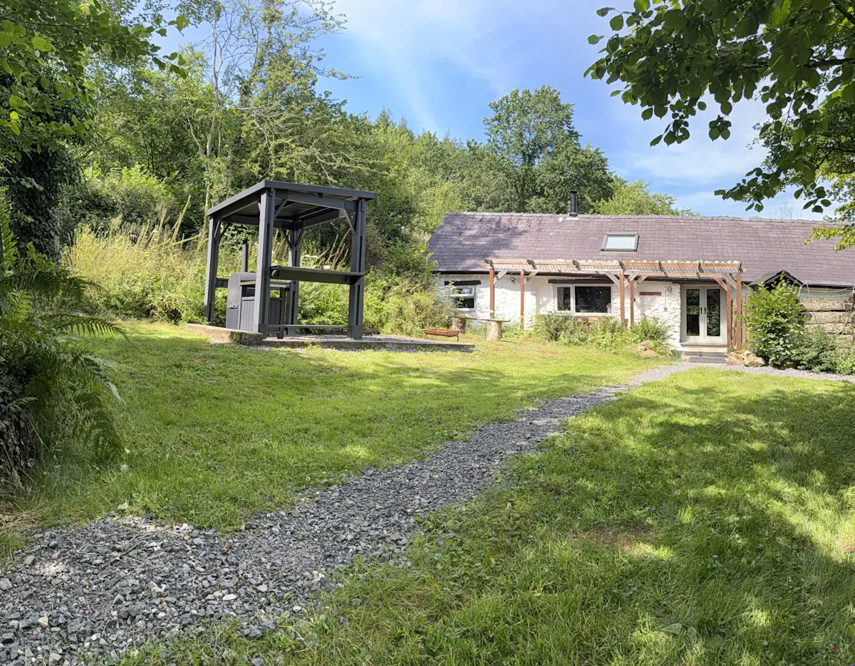 Exterior view of The Barn holiday cottage and the large secluded garden area safely enclosed for anxious dogs.